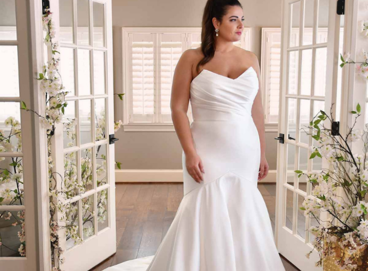 Bride smiling in mirror wearing wedding dress at Pawleys Island bridal shop during exclusive private Lowcountry appointment. Wedding dress shopping.
