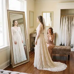A mother and daughter share an emotional moment in front of a mirror as the daughter tries on a wedding dress