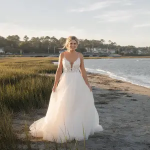 Wedding dresses Myrtle Beach brides love: bride in a flowing gown on the Pawleys Island shoreline in South Carolina.
